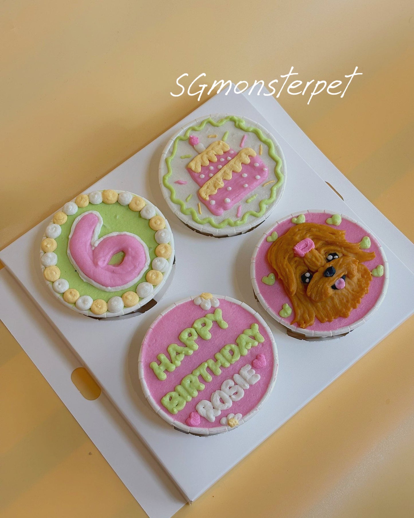 Four round birthday-themed cupcakes on a white tray with 'Happy Birthday' text.