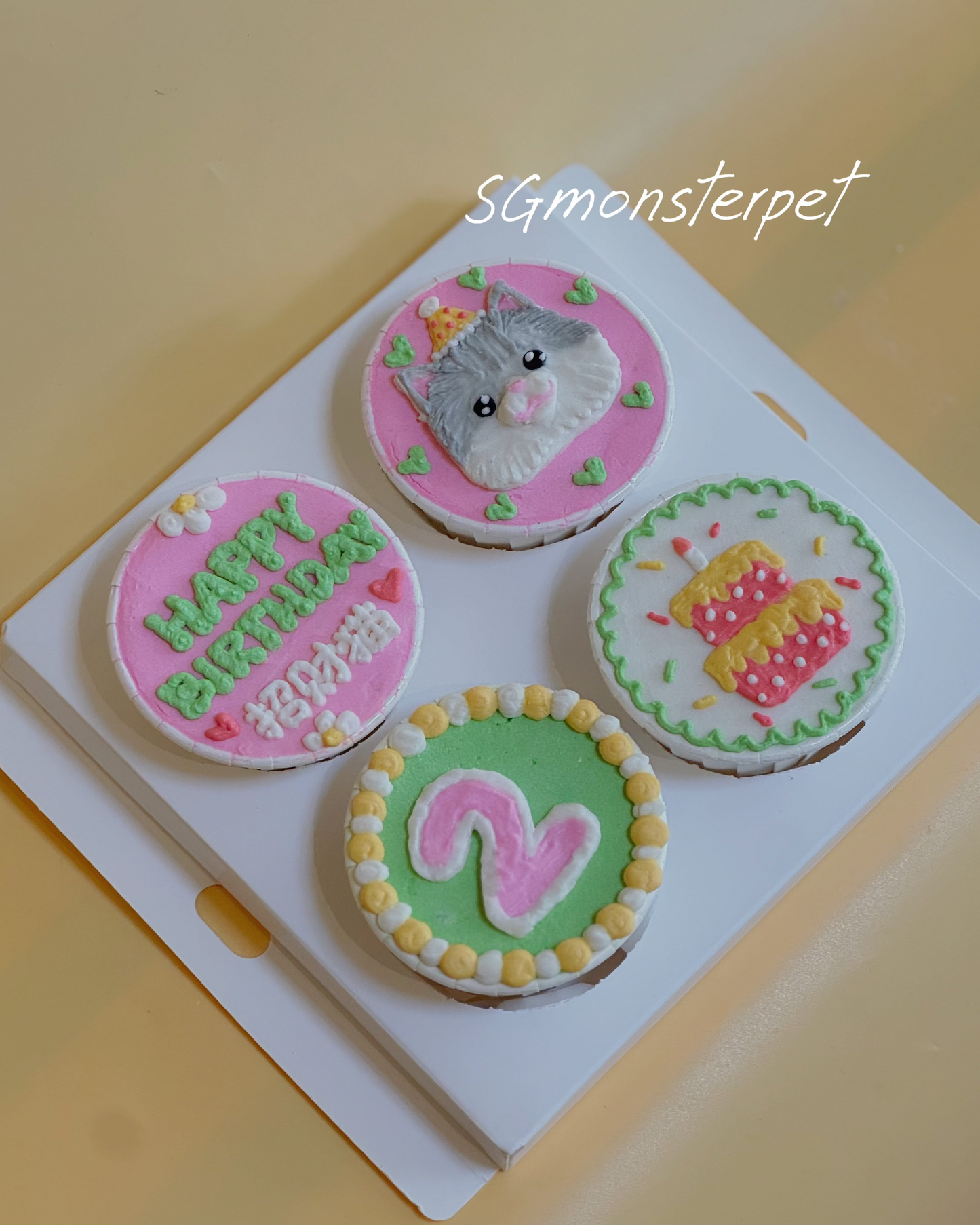 Four small round cupcakes with decorative icing on a white square plate.