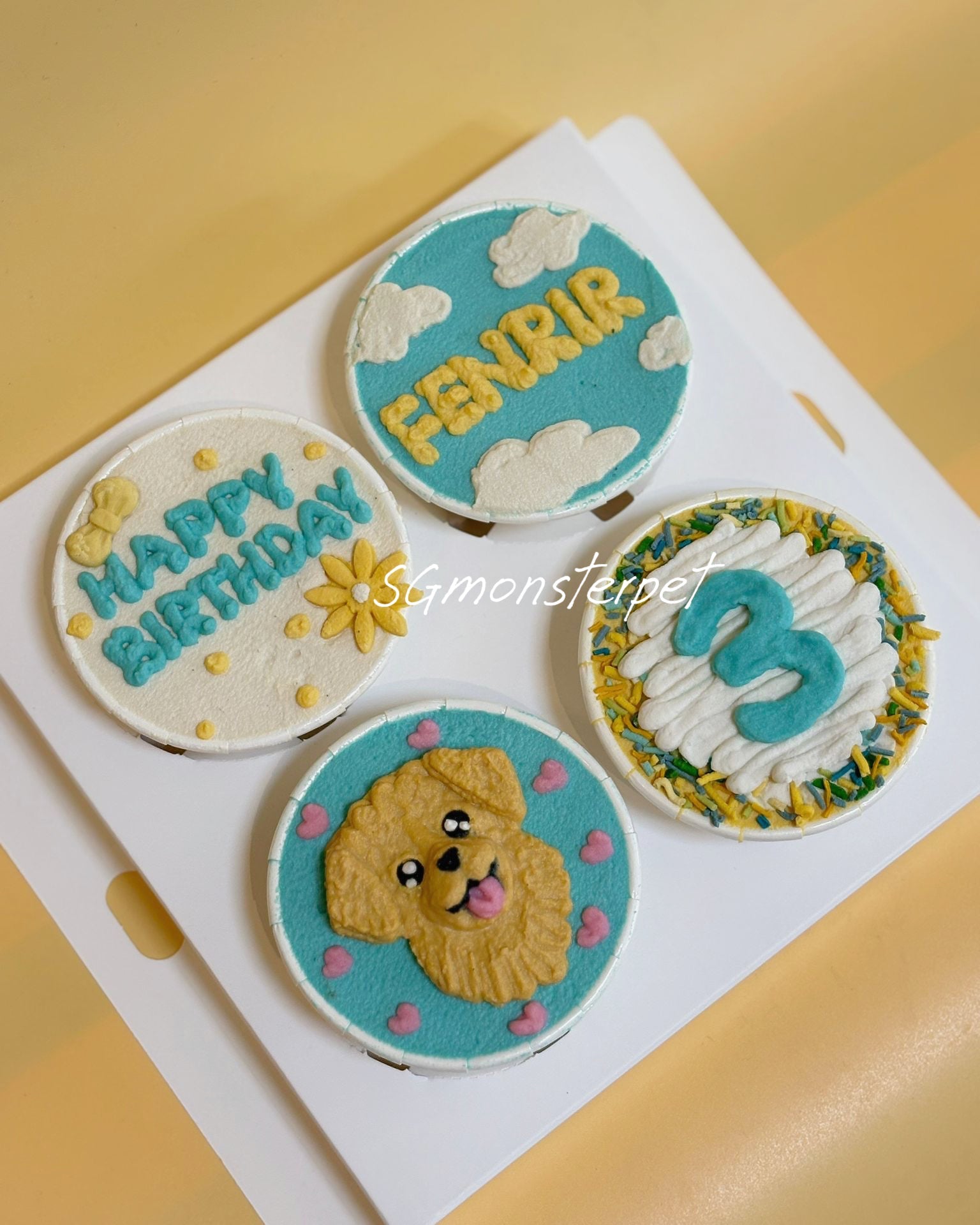 Four round cupcakes with decorative icing on a white card, featuring text and a dog illustration.