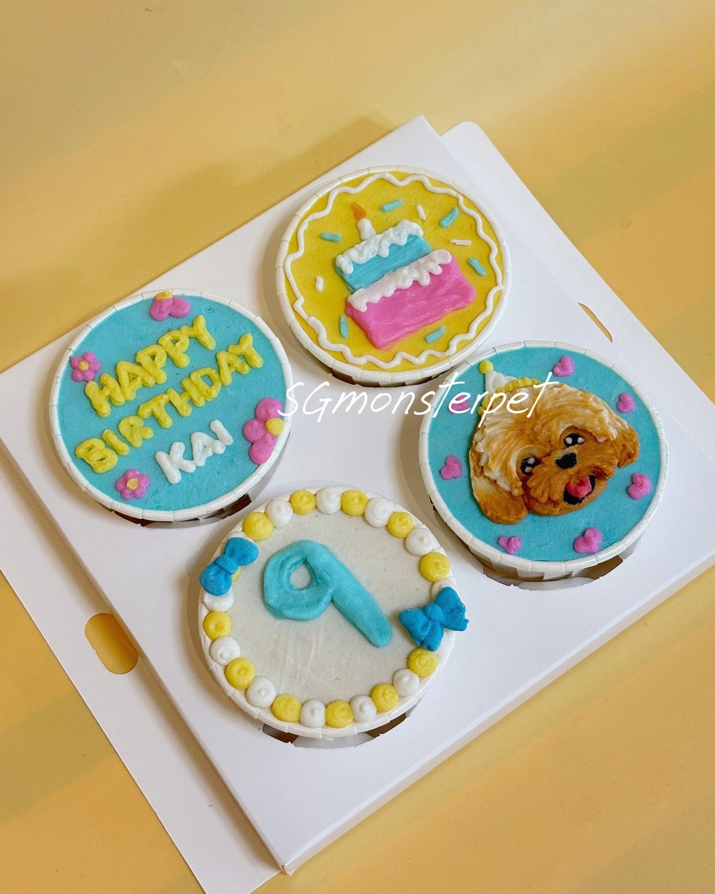 Decorative cupcakes with birthday-themed designs on a white tray.