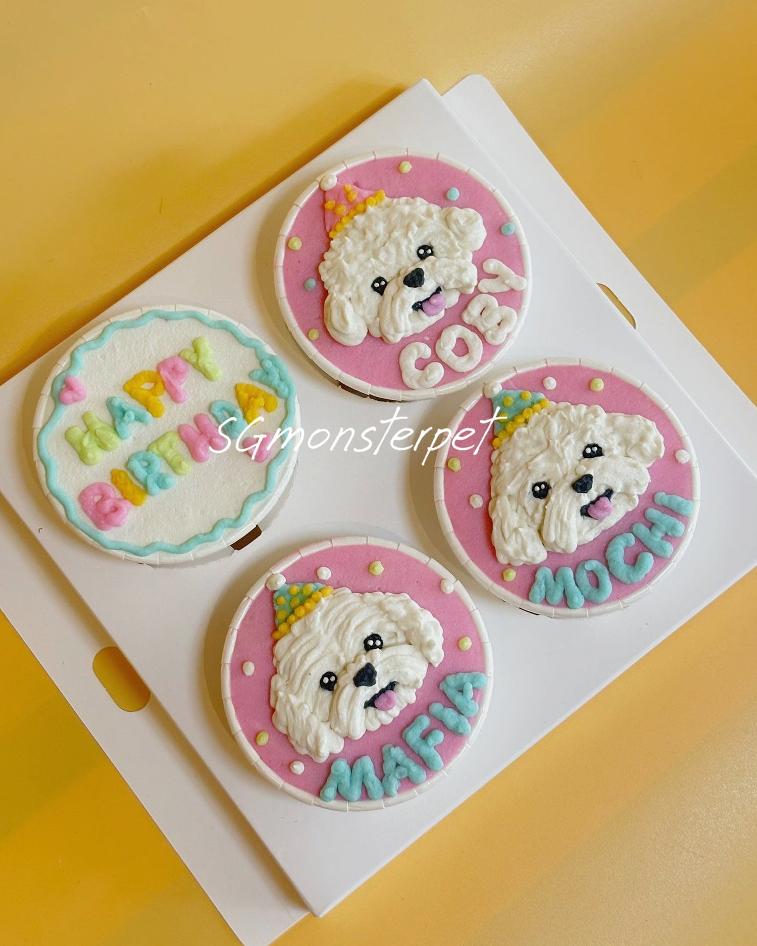 Three cupcakes with dog faces and personalized names on a white tray against a yellow background.