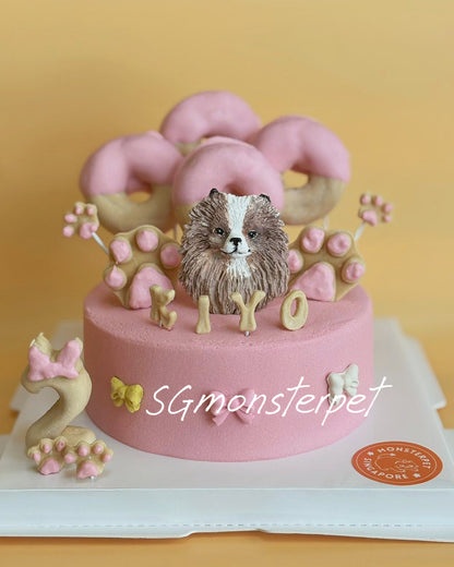 Pink birthday pet cake with dog figurine and decorations.