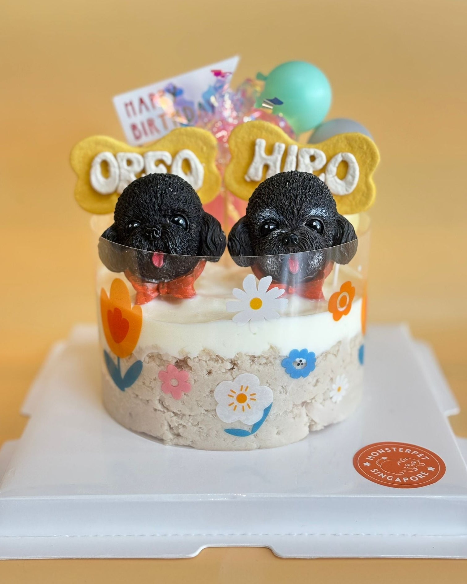 Small pet cake with black dog figurines and colorful decorations on a white stand.