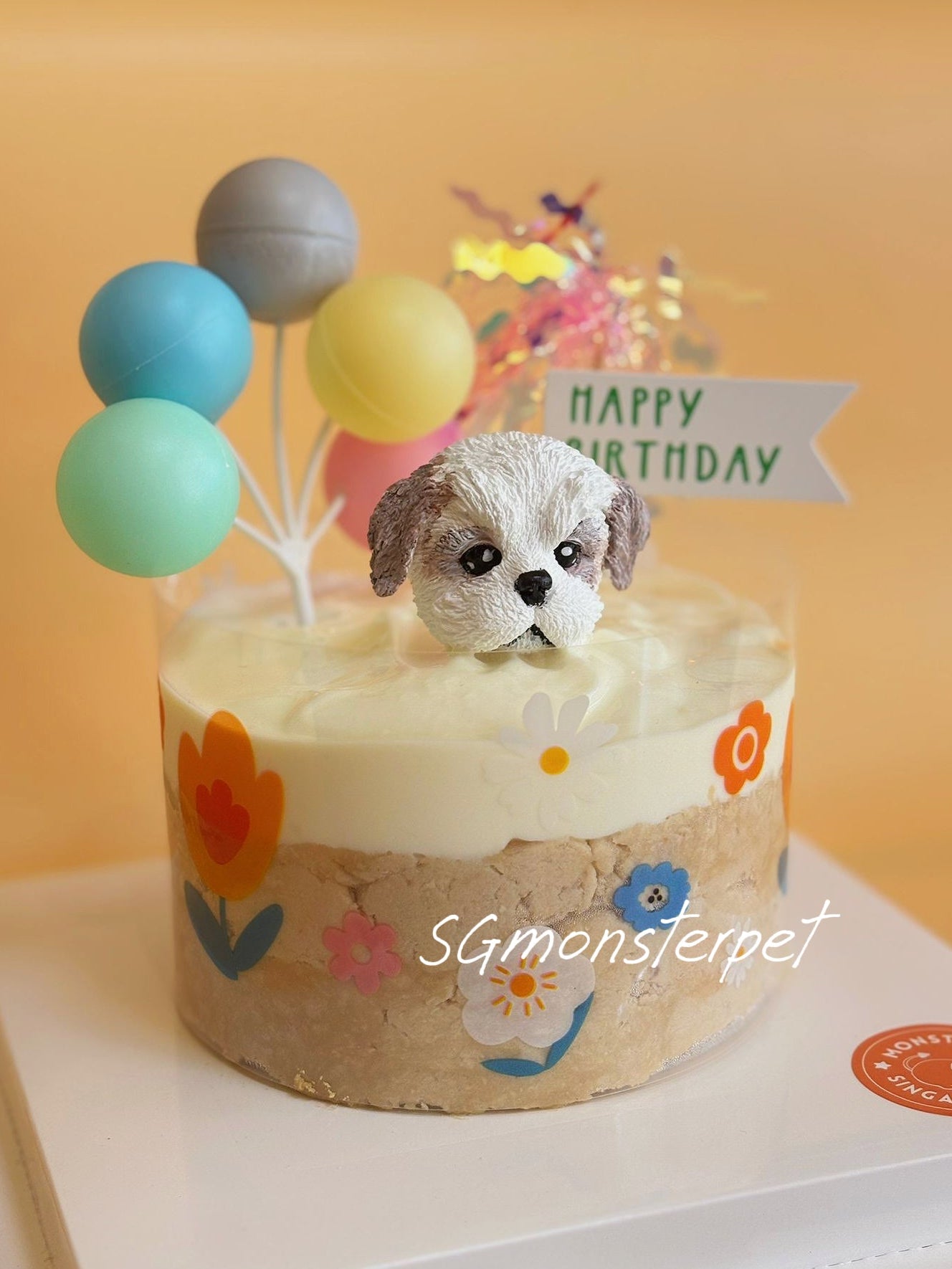 Small birthday pet cake with a dog figurine and colorful balloons on a white plate.