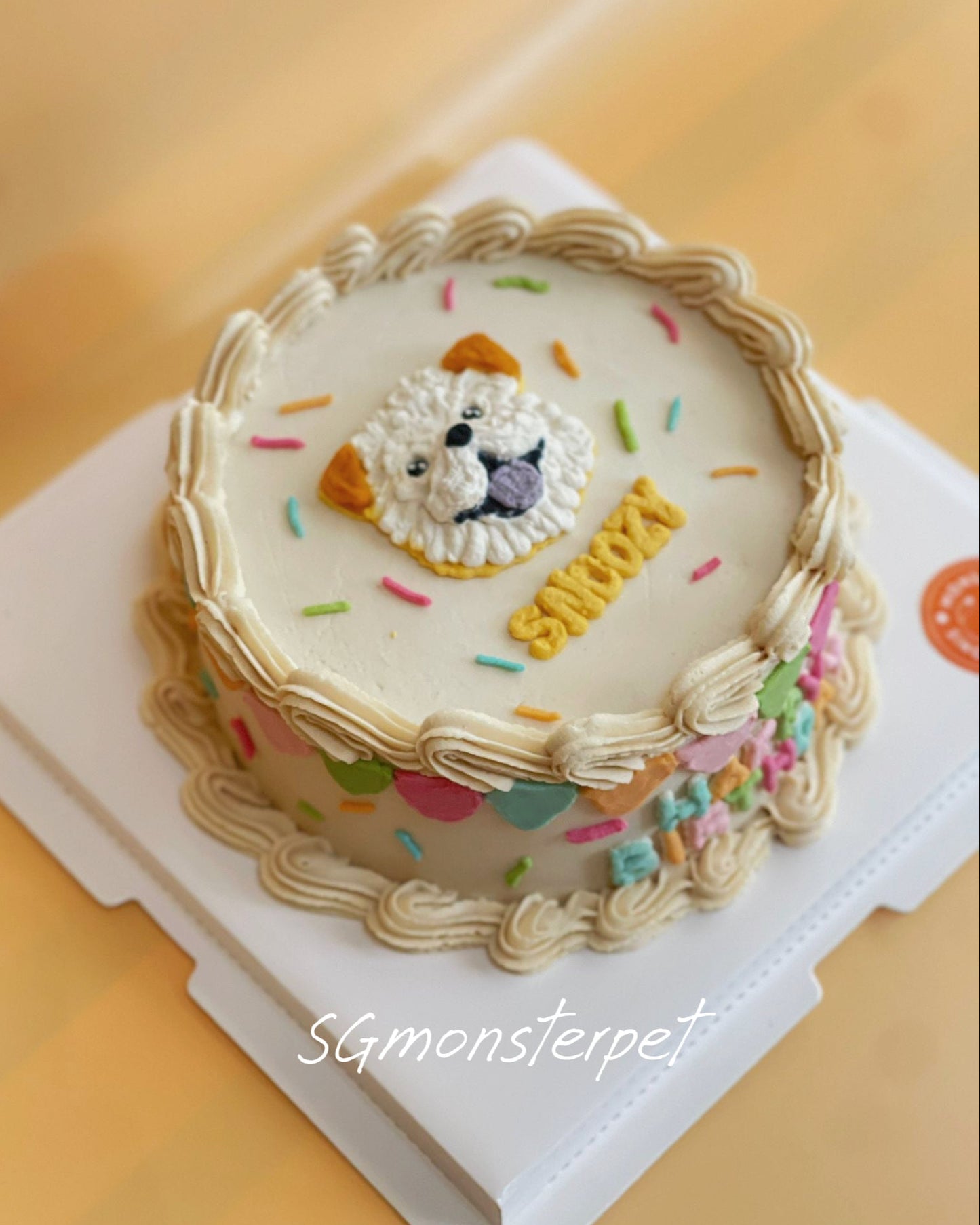 Decorative pet cake with a lion face design and colorful sprinkles on a white stand.