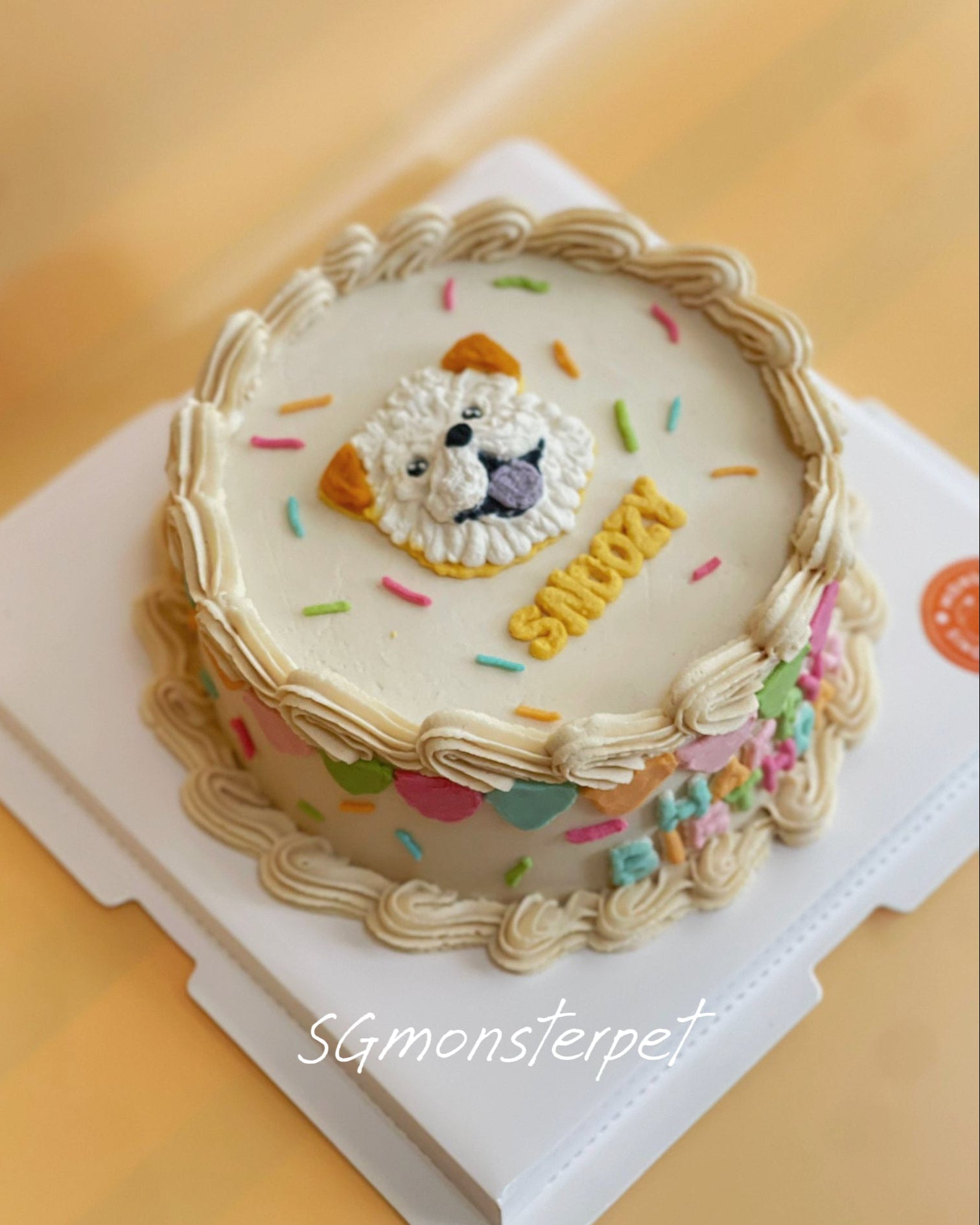 Decorative pet cake with a lion face design and colorful sprinkles on a white stand.