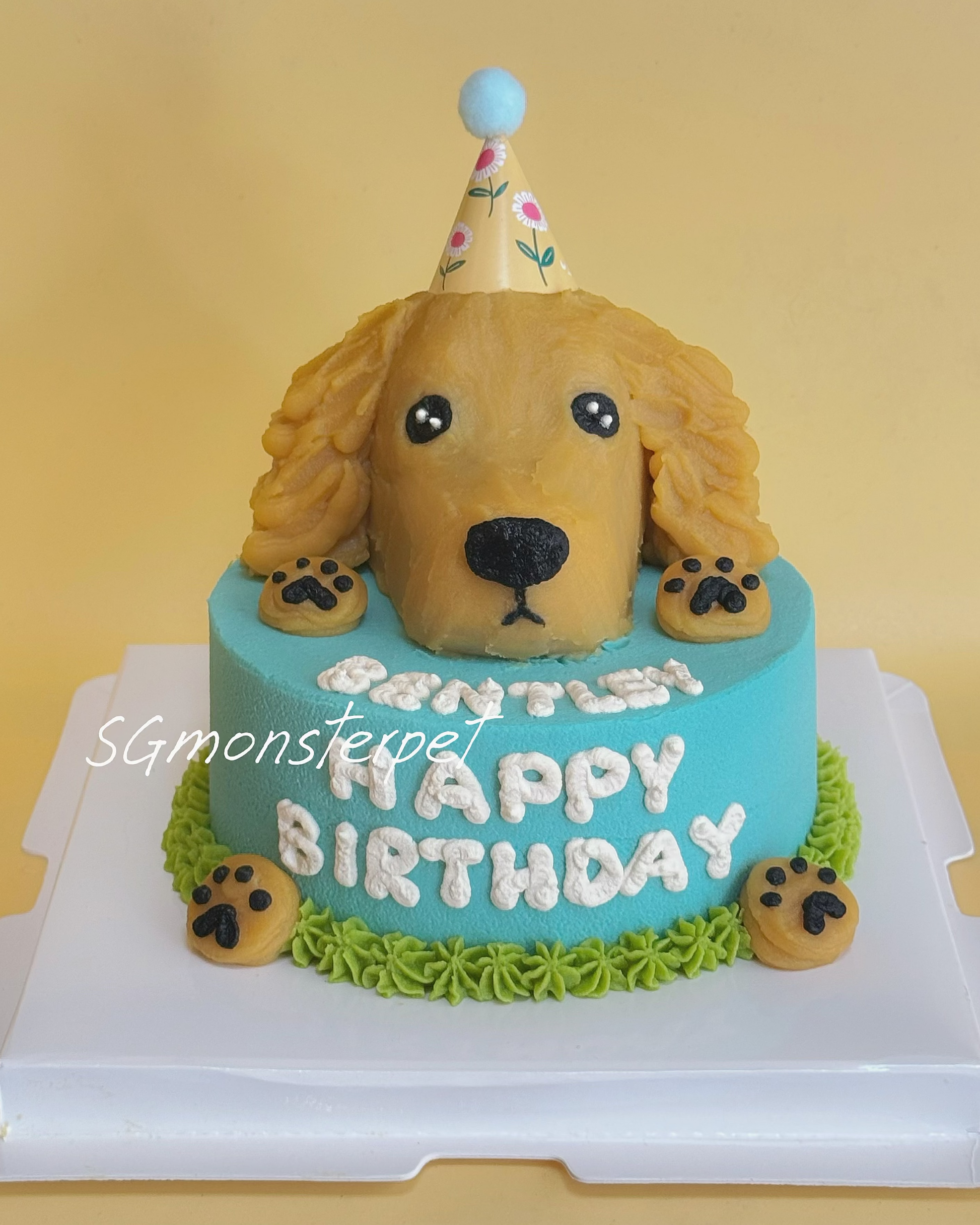 Dog-shaped birthday cake with 'Happy Birthday' text on a yellow background