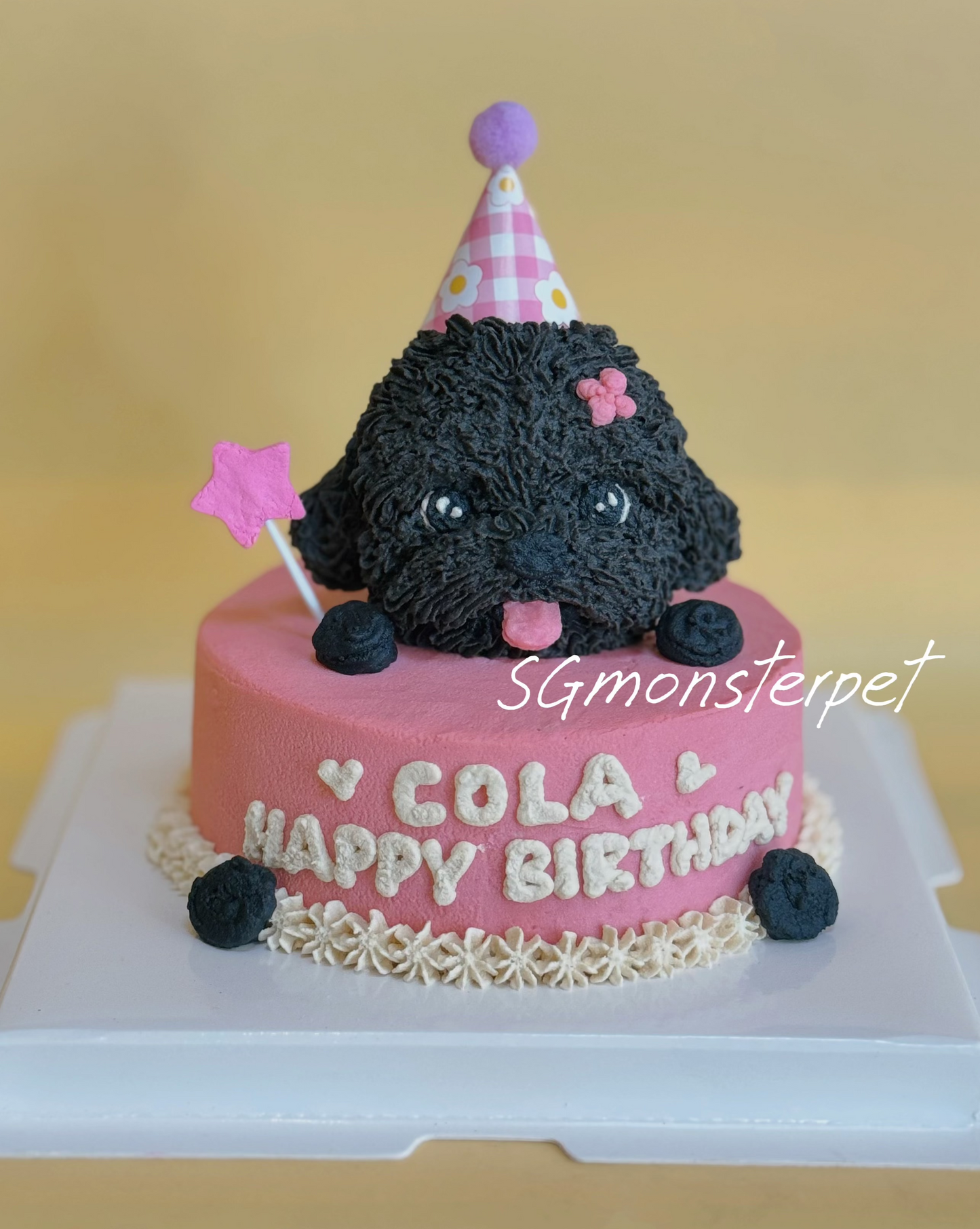Black dog-shaped cake with pink birthday hat and flag on a yellow background