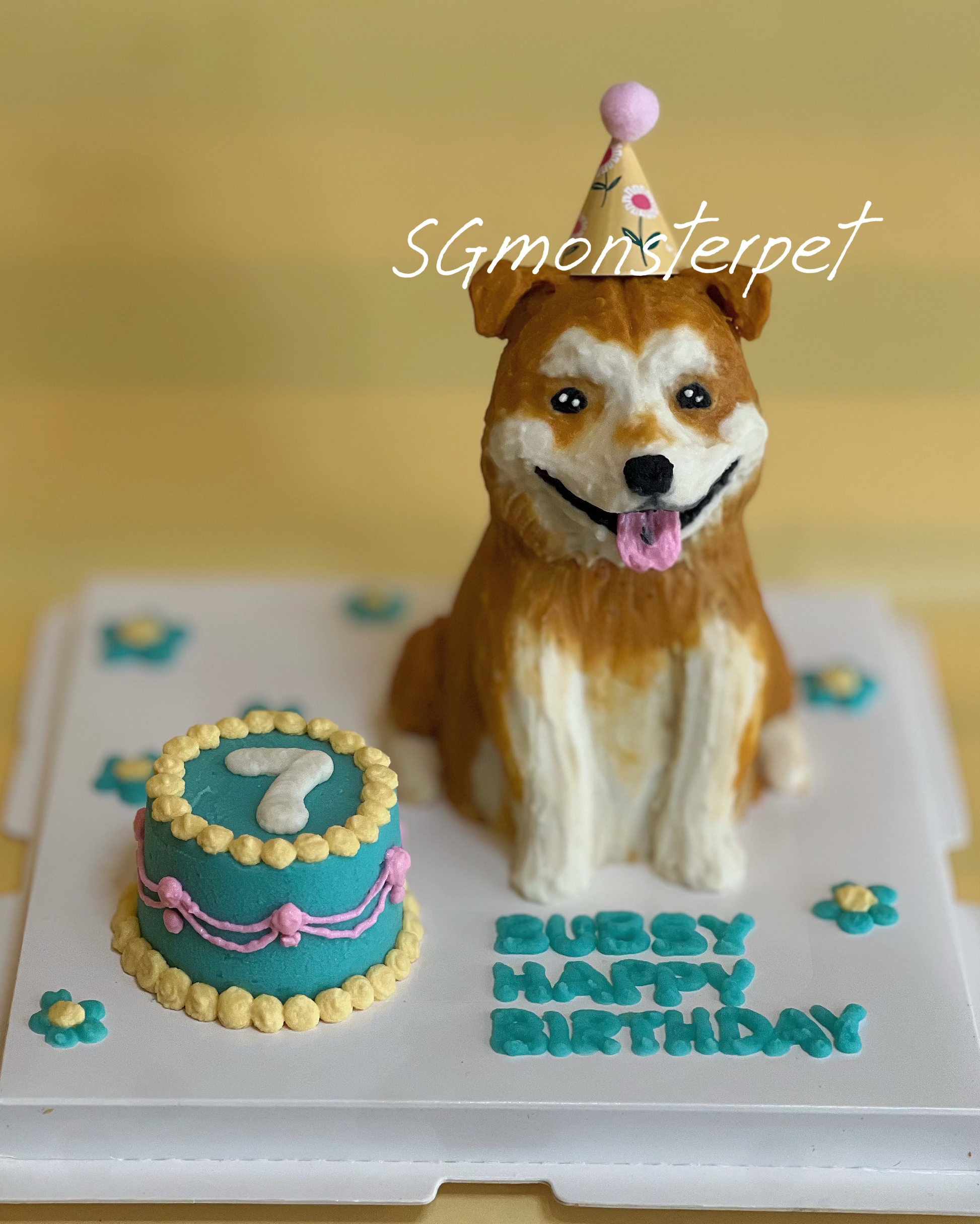 Dog-shaped birthday cake with a small cake and 'Happy Birthday' text on a yellow background