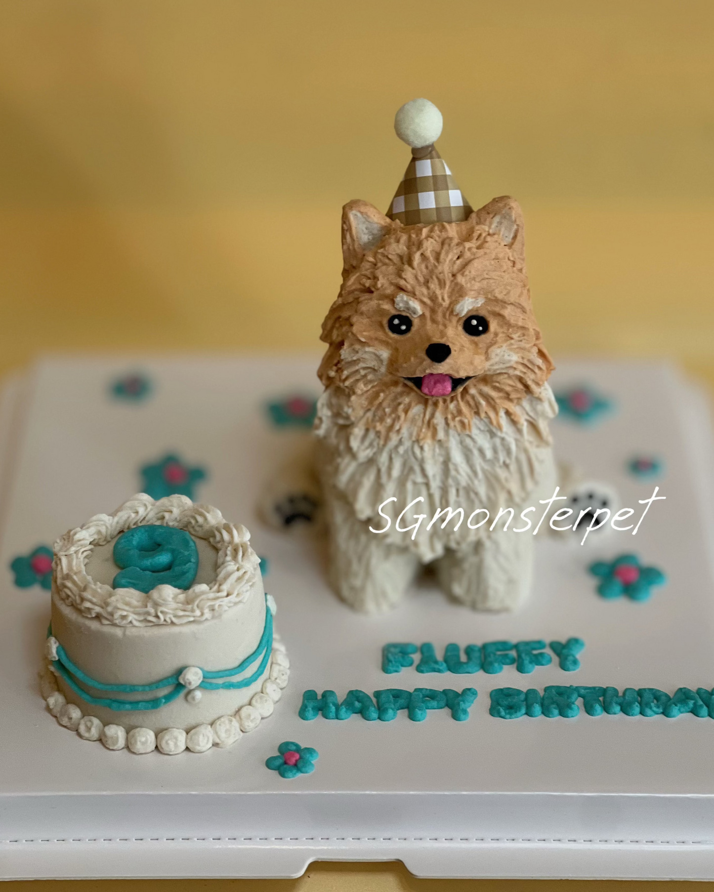 Birthday cake with a dog figurine and small cake on a white stand against a yellow background.