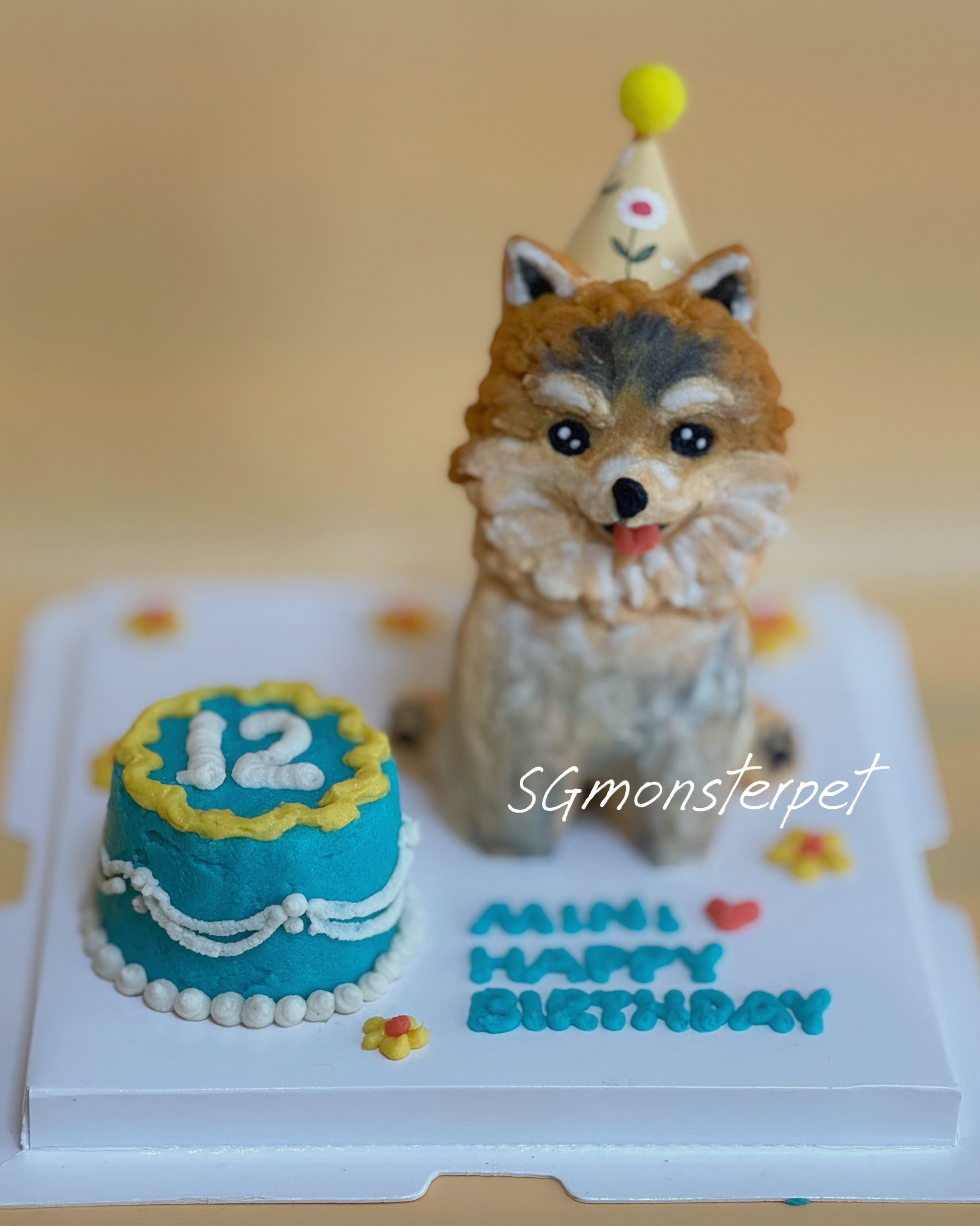 Dog-shaped birthday cake with a small cake and 'Happy Birthday' text on a plain background