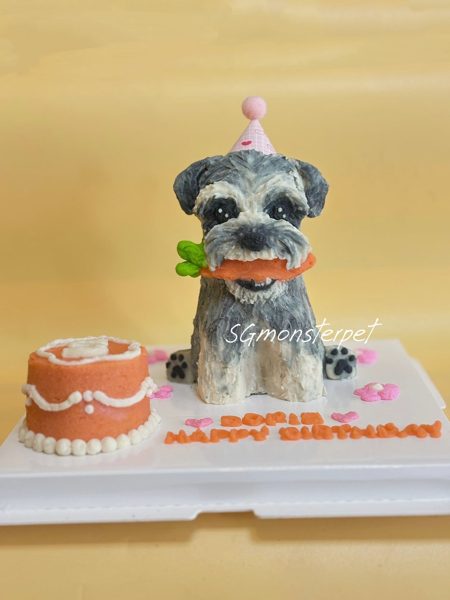 Dog-shaped birthday cake with a small cake and 'Happy Birthday' text on a yellow background