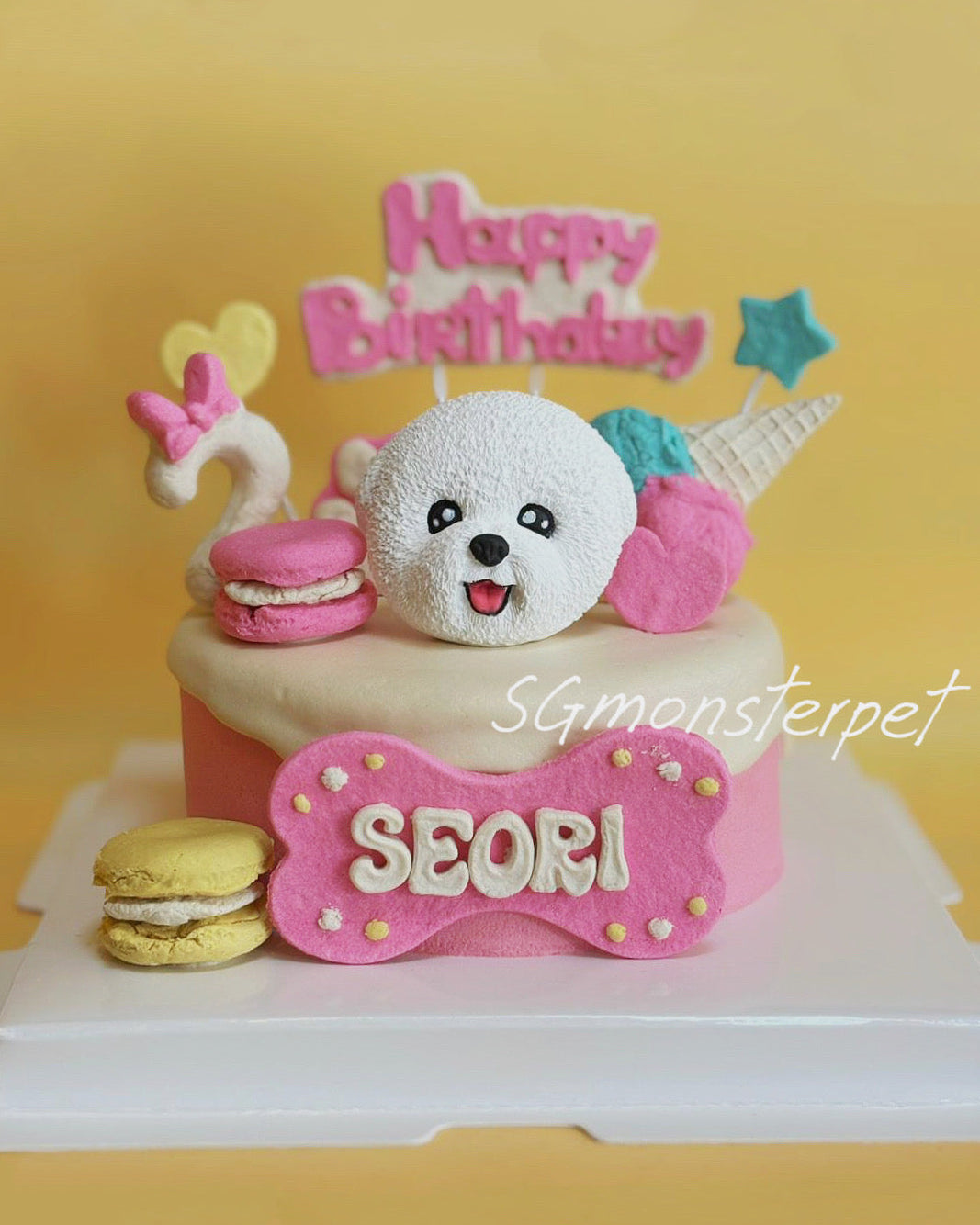 Pet's birthday cake with a teddy bear decoration and 'Happy Birthday' text on a yellow background.